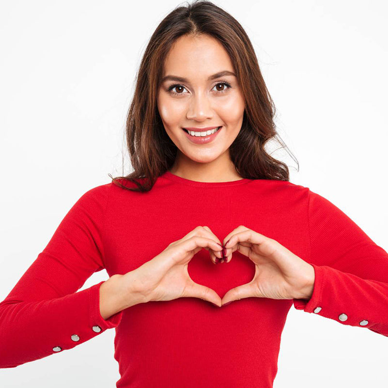 Woman in a red sweater making her hands into the shape of a heart to symbolize cardiovascular health